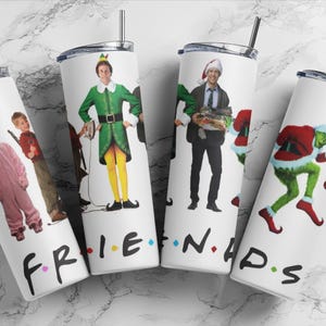 May include: Set of five white stainless steel tumblers with different holiday movie characters printed on them. The tumblers are arranged in a semi-circle with the words "FRIENDS" printed on the bottom of each tumbler.