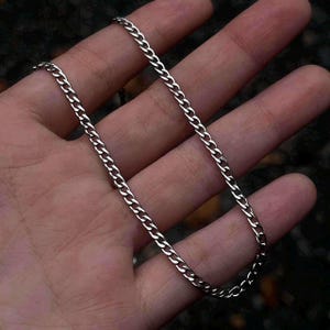 May include: A silver curb chain necklace with a classic design. The chain is made of metal and has a smooth finish.