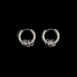 May include: A pair of silver hoop earrings with multiple small rings attached. The earrings are made of a shiny metal and are set against a black background. The earrings have a modern, minimalist design.