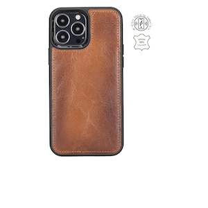 Puede incluir: Una funda de teléfono de cuero marrón con un marco negro y un recorte para el objetivo de la cámara. La funda tiene un logotipo compatible con la carga inalámbrica y una etiqueta de cuero genuino.