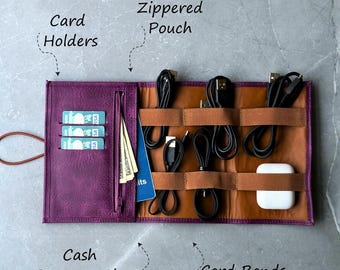 May include: Purple leather travel organizer with multiple compartments for cords, cash, cards, and a passport. The organizer has a zippered pouch, elastic cord bands, and a cash and passport slot.
