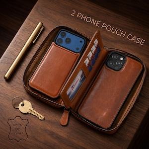 May include: A brown leather zippered 2 PHONE POUCH CASE containing two smartphones, multiple card slots, and a clear ID window. A gold-toned pen and a metal key are placed nearby. The leather case features a stamped logo reading GENUINE 100% LEATHER.