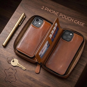 May include: A brown leather phone pouch case with the text "2 PHONE POUCH CASE". The case is open, revealing two phone cases and a card holder. A gold pen and key are next to the case. The case is labeled "GENUINE 100% LEATHER".