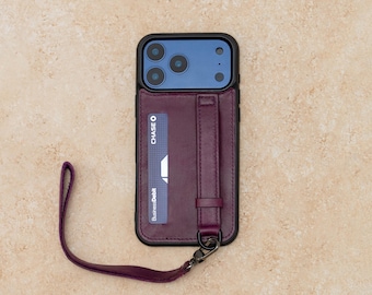 Puede incluir: Una funda de cuero para teléfono en color morado oscuro con marco negro, que incluye una ranura para tarjetas con una tarjeta de débito Chase Business, una correa vertical y una muñequera a juego desmontable sujeta a una anilla.