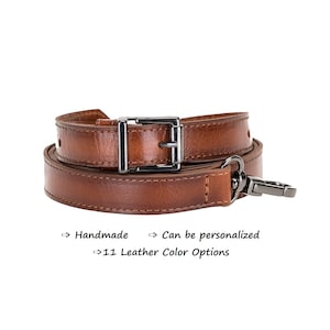 May include: A brown leather camera strap with a silver buckle and a silver clasp. Handmade and can be personalized. 11 leather color options.
