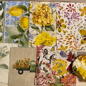 May include: A collection of eight decorative paper napkins with various floral and lemon designs. The napkins feature yellow, green, white, red, and purple colors. The napkins are arranged in a collage on a white surface.