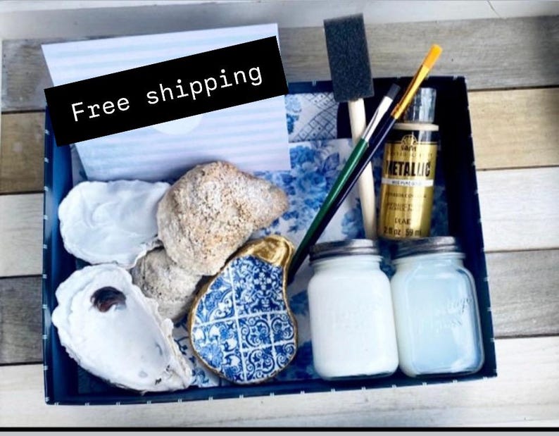 May include: A blue and white ceramic oyster shell dish, two jars of white paint, a gold paint bottle, two paintbrushes, and a card that says "Free shipping" in a blue and white box.