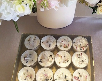 May include: A box of twelve white tea light candles with dried lavender and pink flower petals inside. The candles are arranged in a grid pattern.