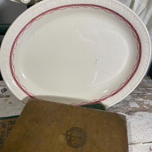 May include: White oval serving platter with a pink and white floral design around the edge.