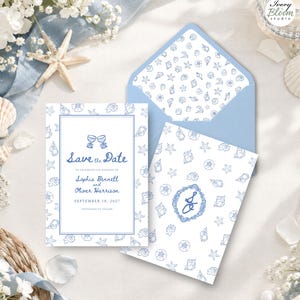 May include: A Save the Date wedding card featuring blue ink illustrations of seashells and starfish on a white background, paired with a light blue envelope with a matching seashell pattern liner and a card displaying a blue monogrammed crest.