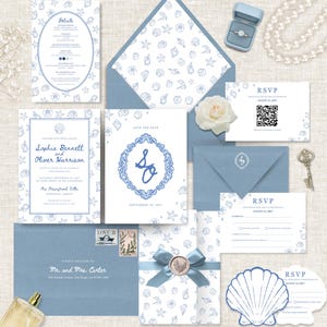 May include: A wedding stationery set featuring blue seashell patterns on white paper, including invitations, RSVP cards with QR codes, envelopes, a wax seal, a ring in a blue box, a pearl necklace, a vintage key, and a perfume bottle.