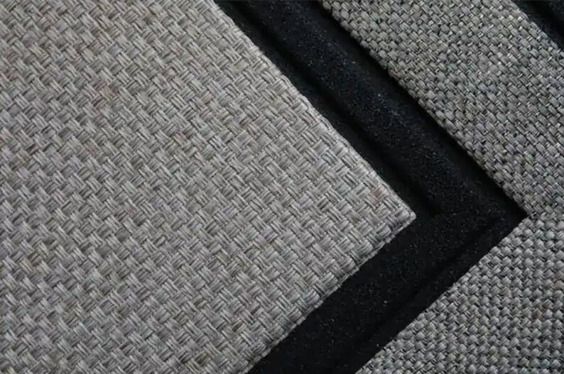 May include: Close-up of a woven grey mat with a black border. The mat has a textured surface and a geometric pattern. The black border adds a contrasting element to the design.