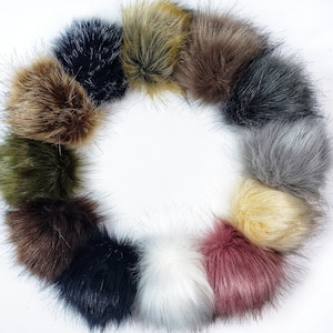 May include: A collection of 12 faux fur pom poms in various colors, including black, brown, gray, white, pink, and green. The pom poms are arranged in a circle on a white background.