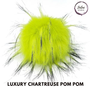 May include: A bright chartreuse faux fur pom pom with black accents. The pom pom is fluffy and has a long, flowing texture.