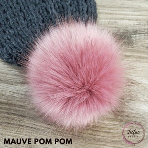 May include: A mauve faux fur pom pom. The pom pom is soft and fluffy, and it would be perfect for adding a touch of color and texture to a hat or scarf.