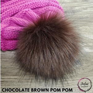 May include: A chocolate brown faux fur pom pom. The pom pom is fluffy and soft, and would be a great addition to any winter hat.