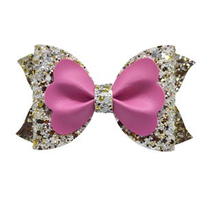May include: A large pink and silver glitter bow with a heart-shaped center. The bow is made of a soft, sparkly material and is perfect for adding a touch of sparkle to any outfit.