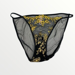 May include: Black sheer mesh underwear featuring a prominent gold floral lace overlay on the front panel. The garment includes thin black side straps and a solid black gusset area, with a visible tag attached to the inner waistband.