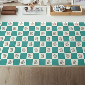 May include: A teal and white checkered desk mat with a pink floral pattern. The mat is made of a durable material and is perfect for protecting your desk from scratches and spills.