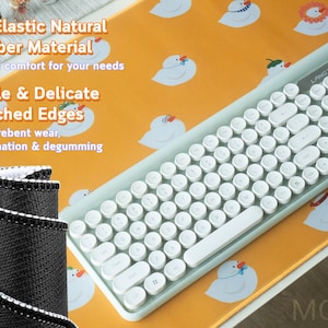 May include: A white keyboard with round keys and a light blue frame sits on a yellow mousepad with a pattern of white cartoon ducks. The mousepad has the text "MOOUII" in the bottom right corner. The text "High Elastic Natural Rubber Material" and "Durable & Delicate Stitched Edges" is printed on the mousepad.