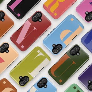 May include: A collection of smartphone cases in various colors, each featuring a large, stylized letter. The cases are in shades of brown, red, blue, green, and purple, with contrasting letter designs in white, orange, and pink.
