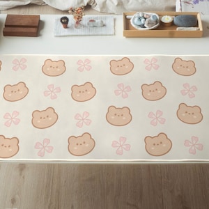 May include: A white and pink mouse mat with a repeating pattern of brown bears and pink flowers.