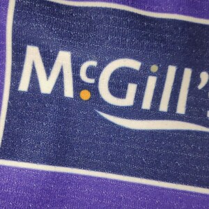 May include: A purple and white logo with the text "McGill's" in white letters. The logo is on a blue background.