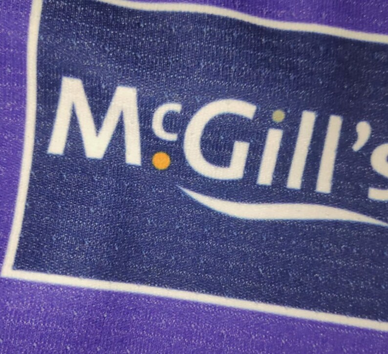 May include: A purple and white logo with the text "McGill's" in white letters. The logo is on a blue background.