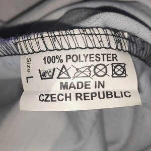 May include: White tag with black text that reads "Size: L 100% POLYESTER" and care instructions. Below the text is "MADE IN CZECH REPUBLIC".
