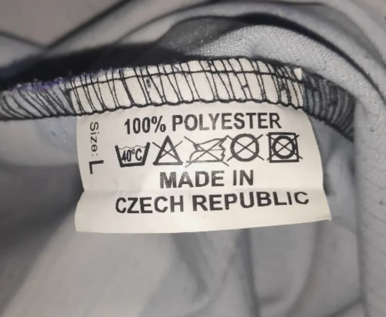 May include: White tag with black text that reads "Size: L 100% POLYESTER" and care instructions. Below the text is "MADE IN CZECH REPUBLIC".