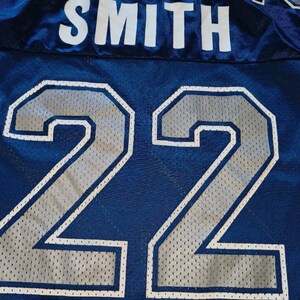 Puede incluir: Una camiseta azul con el nombre "SMITH" y el n&uacute;mero "22" en blanco con un patr&oacute;n de malla plateada.