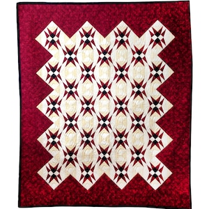 May include: A red and white quilt with a geometric pattern of stars. The quilt is made with a variety of fabrics and has a quilted texture.