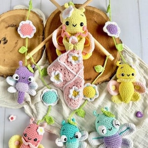 May include: A handmade crochet baby mobile featuring several colorful butterflies and flowers. The butterflies are in shades of yellow, pink, purple, and blue, with white accents. The flowers are pink, yellow, and blue. The mobile is suspended from a wooden frame.