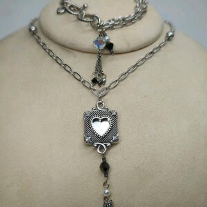 Peut inclure: Ensemble collier et bracelet argent&eacute;. Le collier pr&eacute;sente un pendentif carr&eacute; avec une d&eacute;coupe en forme de c&oelig;ur, une perle noire pendante et une pampille en cha&icirc;ne. Le bracelet a un fermoir &agrave; bascule et un design en cha&icirc;ne.