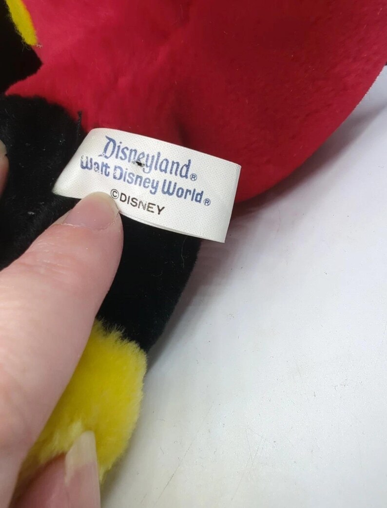 May include: A plush toy with red, black, and yellow accents. The tag reads "Disneyland Walt Disney World &copy;DISNEY". The toy is soft and appears to be a character from Disney.