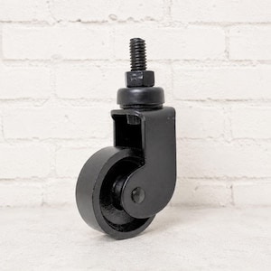 May include: A black caster wheel with a threaded stem and a nut. The wheel is round and has a solid, industrial design. The caster is likely used for furniture or other applications requiring mobility.