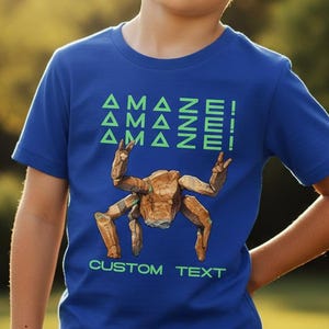 May include: A blue t-shirt with the word "AMAZE!" repeated three times in green, above a brown, stylized robot graphic. The words "CUSTOM TEXT" are below the graphic. The shirt is worn by a young person.
