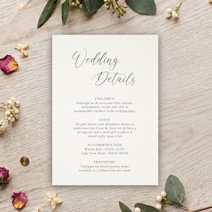 May include: A rectangular white wedding details card with black text featuring the header Wedding Details followed by sections for Children, Gifts, Accommodation, and Transport. The card has a textured paper finish and is centred on a light wood surface.