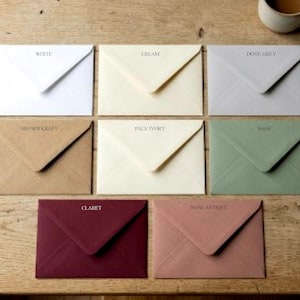 May include: A collection of eight rectangular envelopes in various colours, each labelled with its shade: White, Cream, Dove Grey, Brown Kraft, Pale Ivory, Sage, Claret, and Rose Antique. The envelopes are arranged in a grid, each featuring a triangular flap.