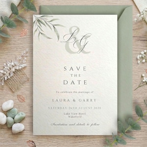 May include: A white Save the Date card featuring a sage green leaf illustration, the letters L and G in a large script font, and black text reading: Save the Date to celebrate the marriage of Laura & Garry, Saturday 26th August 2028, Lake View Hotel.