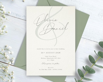 May include: A cream-coloured wedding invitation card with black text featuring the names Olivia and Daniel in a large script font, placed on a sage green envelope. The text includes the date 26th August 2028 and venue details for the event.