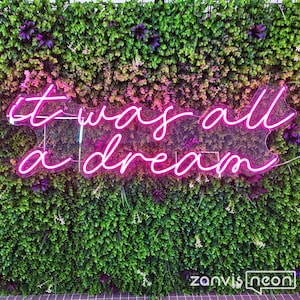 May include: Pink neon sign with the text "it was all a dream" on a green wall with small purple flowers.