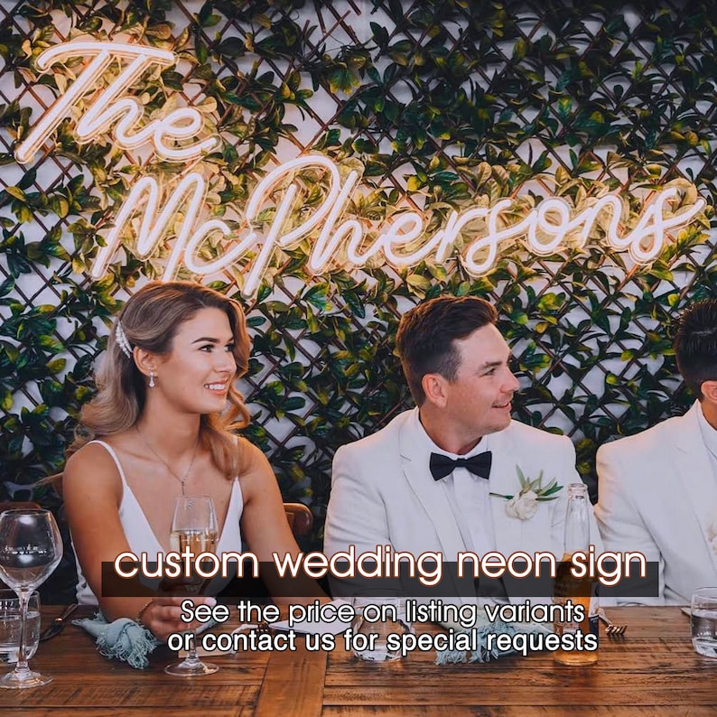 May include: A white neon sign with the text "The McPhersons" on a green leafy wall. The sign is lit up and is a custom wedding neon sign. The text below the sign reads "See the price on listing variants or contact us for special requests."