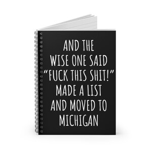 May include: A spiral-bound notebook with a black cover. The cover features white text that reads: "AND THE WISE ONE SAID 'FUCK THIS SHIT!' MADE A LIST AND MOVED TO MICHIGAN."