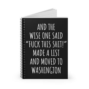 May include: A black spiral-bound notebook with white text that reads "AND THE WISE ONE SAID 'FUCK THIS SHIT!' MADE A LIST AND MOVED TO WASHINGTON". The notebook has white lined pages.