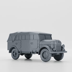 以下が含まれることがあります： キャンバスの幌が付いた軍用トラックのグレーのモデル。トラックは後部にスペアタイヤと縦のバーが付いたグリルがあります。