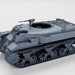 Op de afbeelding: Een grijs model van een militaire tank met een machinegeweer op de bovenkant. De tank heeft een grote, ronde toren en een lang, rupsbandchassis.