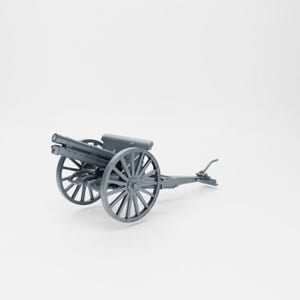 May include: A gray model cannon with two spoked wheels. The cannon has a barrel and a carriage. The wheels are large and have multiple spokes. The cannon is a miniature replica of a historical artillery piece.