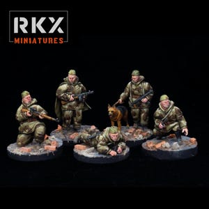 Peut inclure: Figurines miniatures de soldats en uniformes de camouflage, certains agenouillés ou accroupis, avec des fusils et un chien. Les figurines sont sur des bases circulaires avec des détails de briques et de décombres. Le logo "RKX MINIATURES" est en haut à gauche.