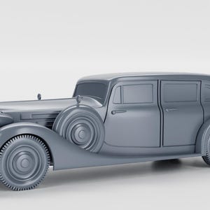 Pode incluir: Um sedan vintage cinza com uma grelha cromada e um capô longo. O carro tem quatro portas e um pneu sobressalente na parte traseira.